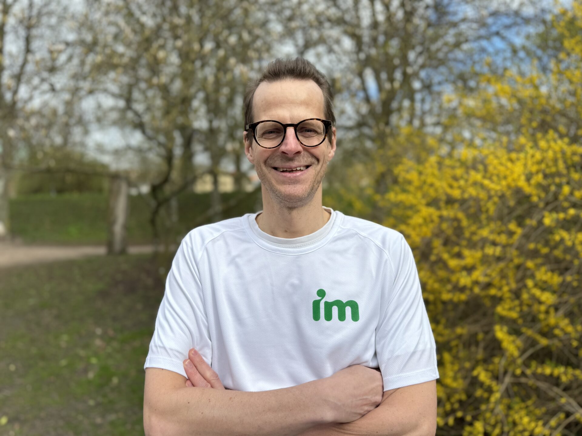 Martin Nihlgård, en vit man i en vit tröja som det står IM på. I bakgrunden parkmiljö.